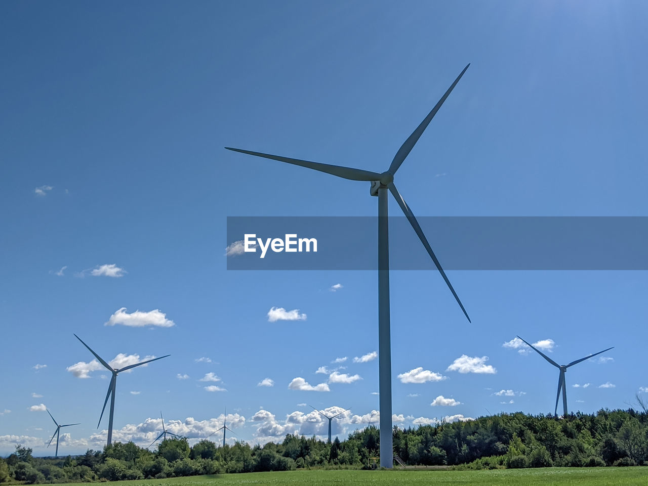 WIND TURBINES ON FIELD AGAINST BLUE SKY