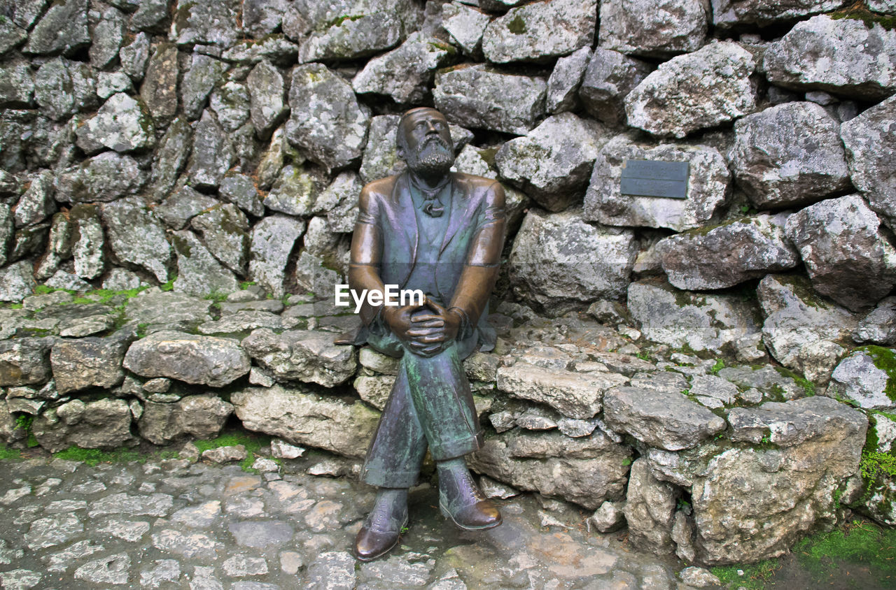 LOW SECTION OF MAN WEARING SHOES ON COBBLESTONE