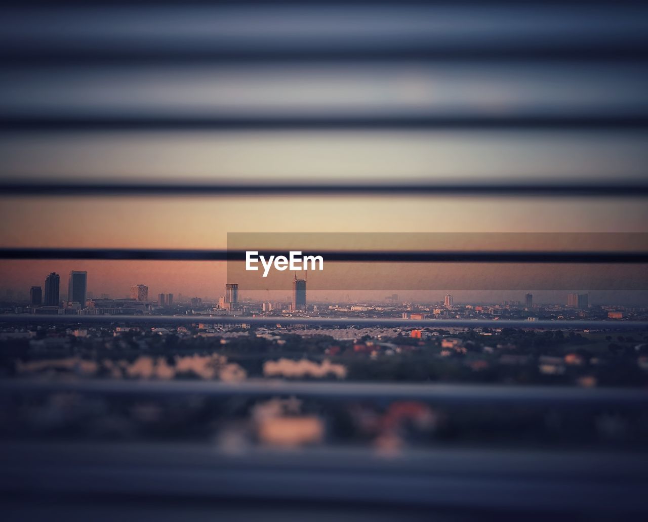 Cityscape against sky during sunset seen from blinds