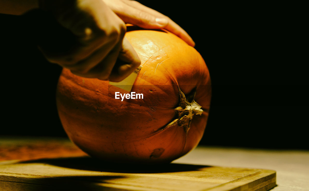 Cropped hand of person cutting pumpkin during halloween