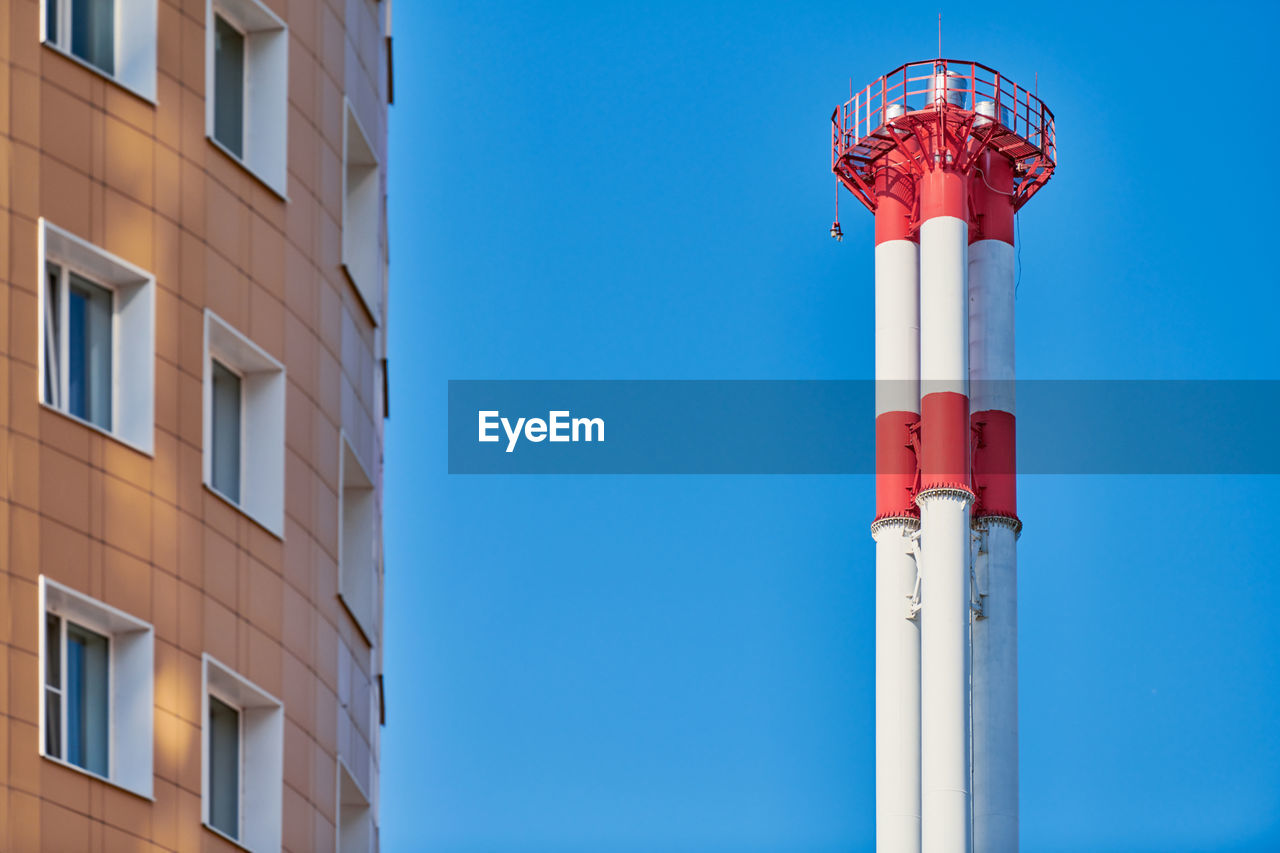 Multistorey building facade and factory chimney. new multi-storey facade, windows and block of flats