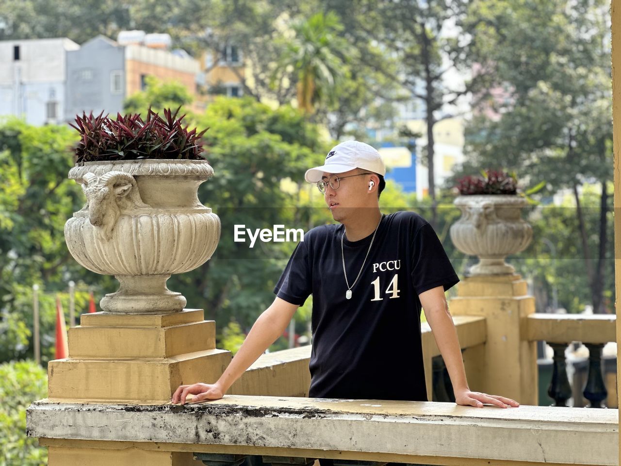 portrait of young man standing by tree trunk