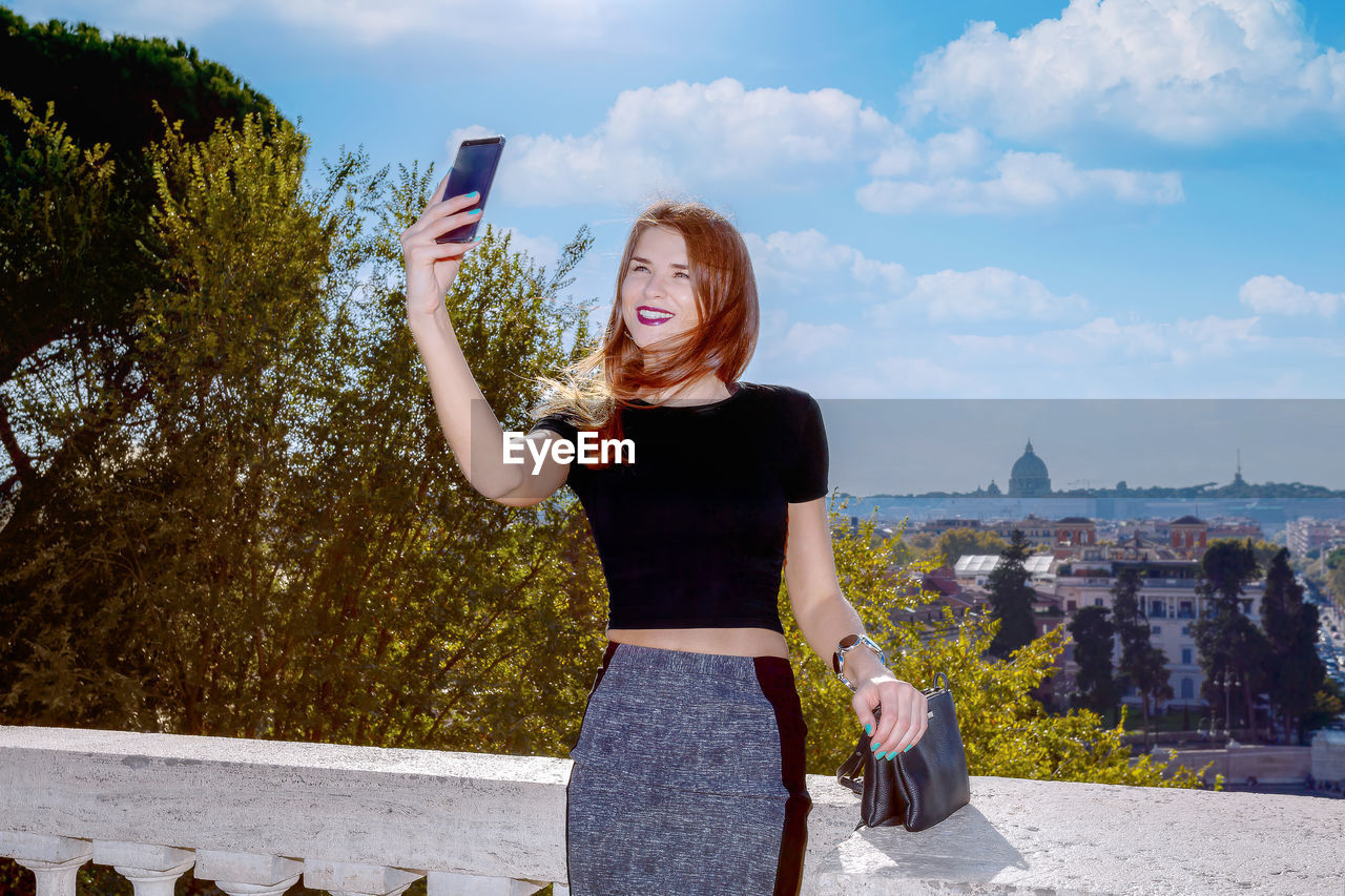 Girl takes a selfie from the pincio, famous vantage point of the city of rome. 