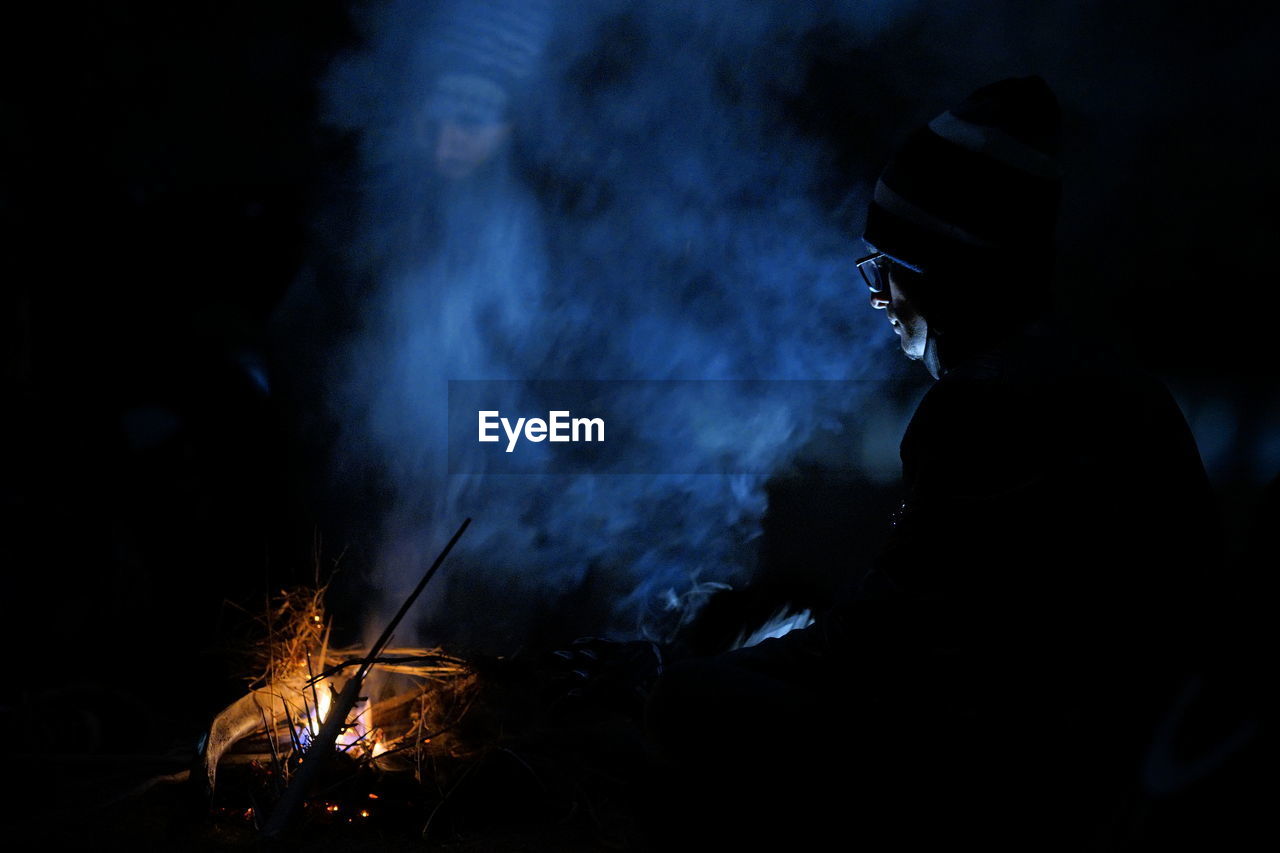 Man sitting by campfire at night