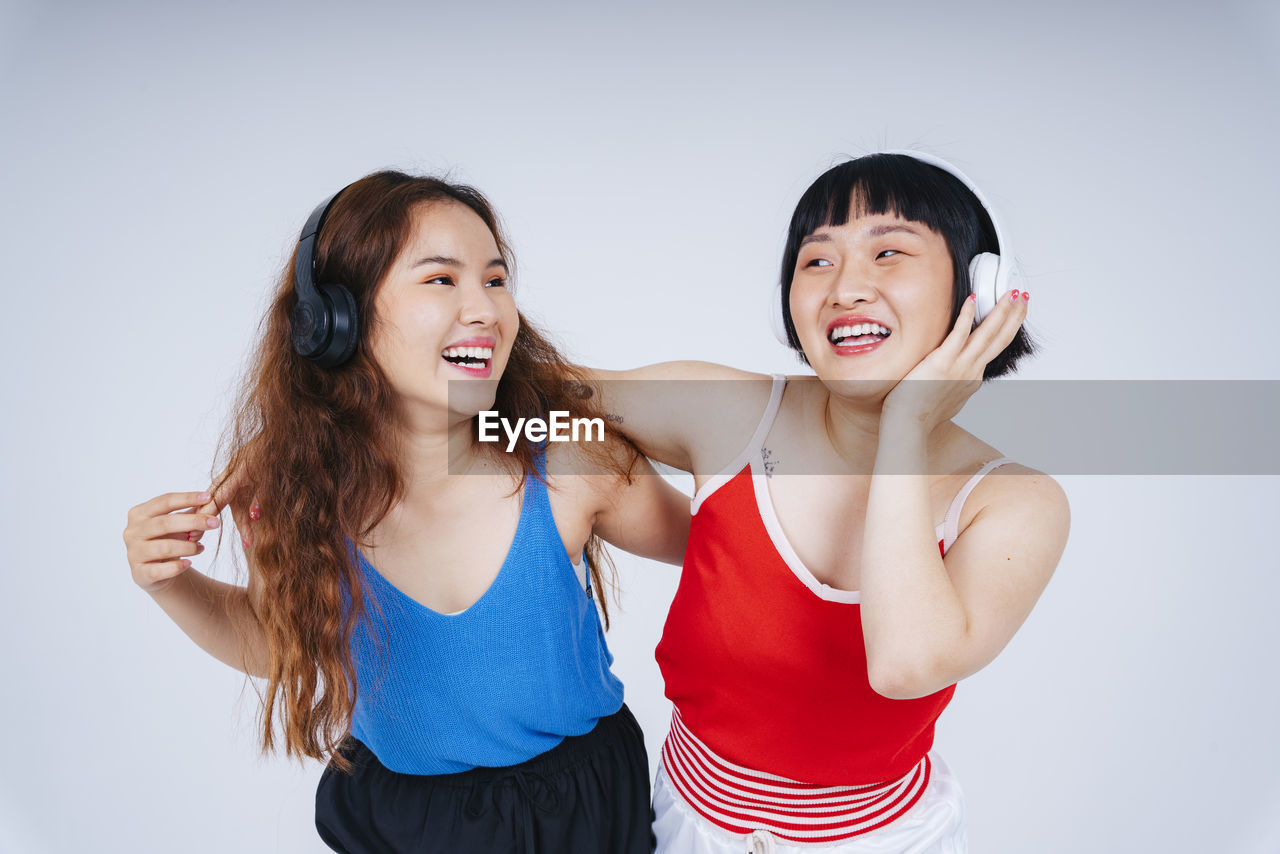 Lesbian couple listening music against gray background