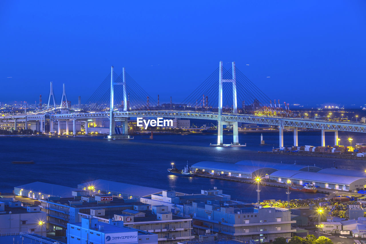 Illuminated bridge over river in city at night