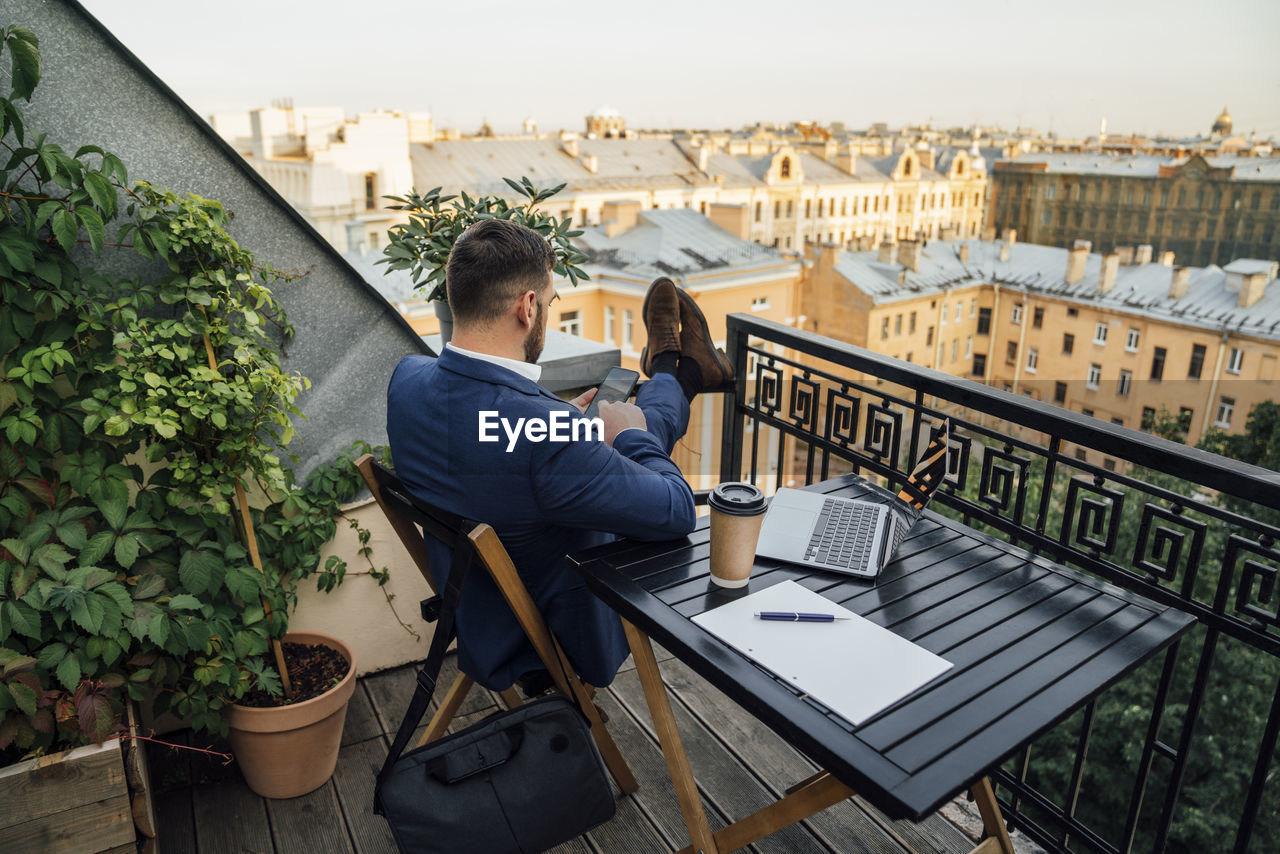 Male professional using smart phone in office balcony