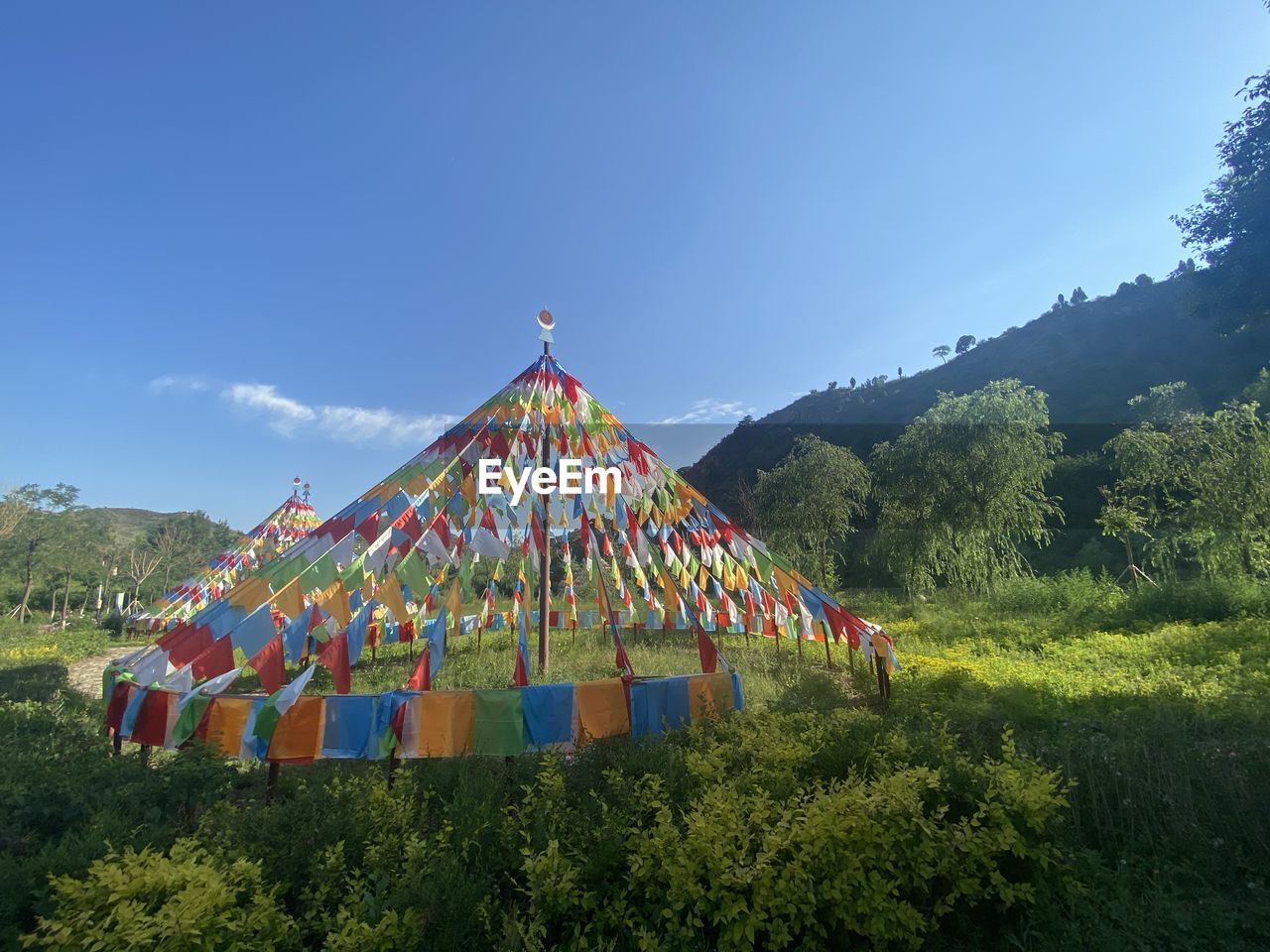 Multi colored flags on field against blue sky