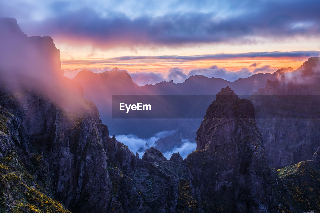 environment, landscape, mountain, sky, scenics - nature, nature, cloud, beauty in nature, sunset, land, fog, travel, mountain range, travel destinations, wilderness, mountain peak, sun, panoramic, rock, twilight, forest, dramatic sky, tree, dusk, cold temperature, tourism, outdoors, winter, plant, no people, valley, sunlight, activity, sunbeam, snow, tranquility, pinaceae, cloudscape, cliff, multi colored, non-urban scene, pine tree, coniferous tree, blue, social issues, high up, igniting, awe, atmospheric mood, tranquil scene, idyllic, national park, vacation, trip, extreme terrain