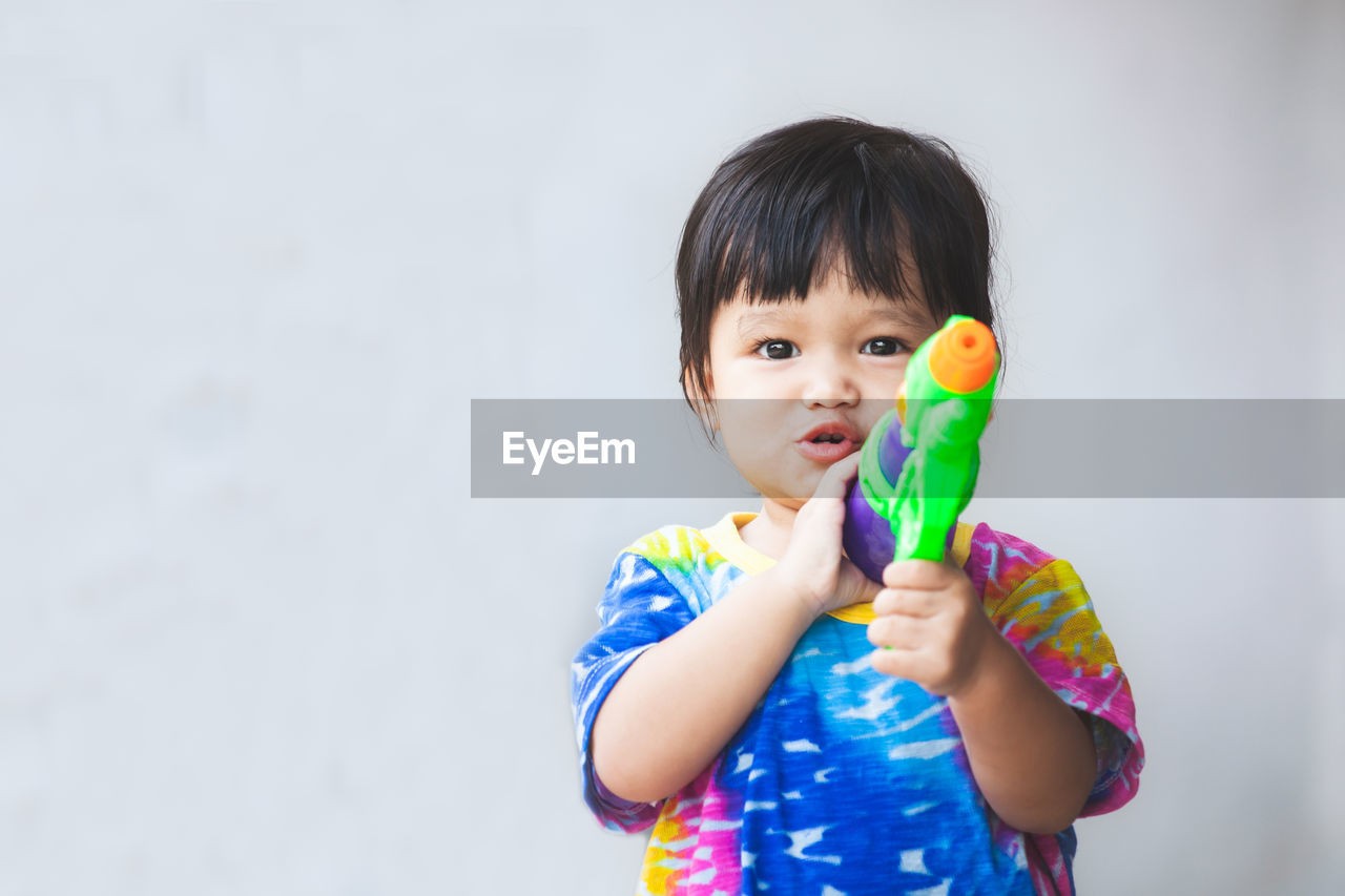 Portrait of cute baby girl holding squirt gun