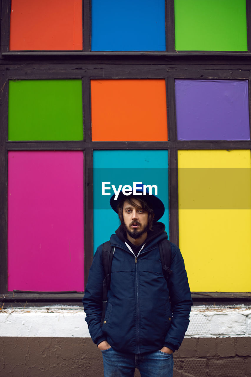 Portrait of young man in a hat standing against wall