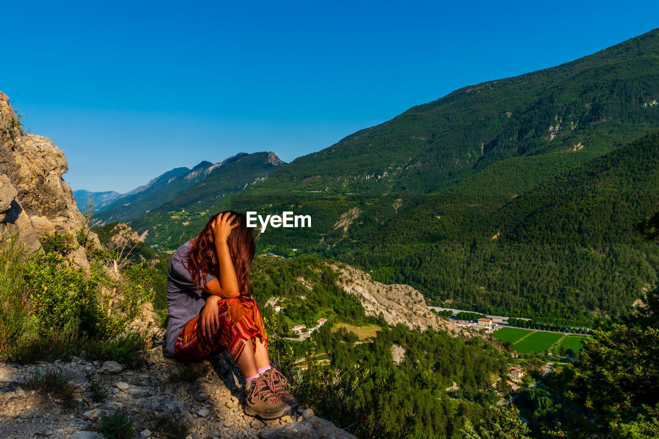 Full length of woman sitting against mountain range