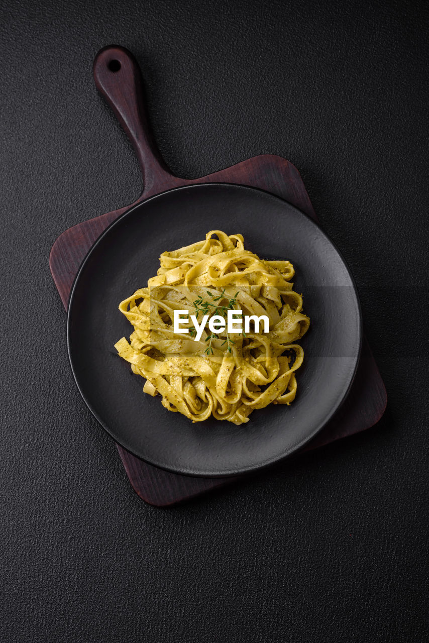 food, food and drink, pasta, italian food, studio shot, healthy eating, freshness, kitchen utensil, spaghetti, indoors, wellbeing, black background, no people, cuisine, herb, high angle view, dish, vegetable, directly above, produce, plate, eating utensil, gray, meal
