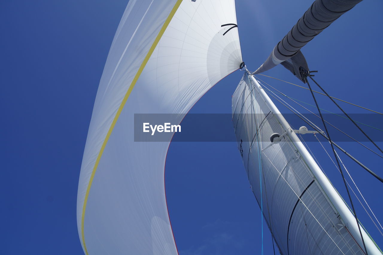 Low angle view of sailboat in sea against blue sky