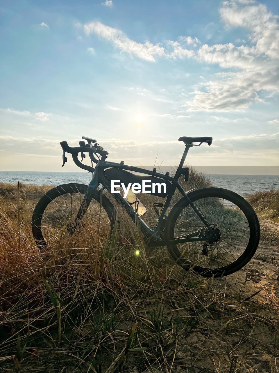 bicycle, sky, transportation, nature, land, mountain bike, mode of transportation, cloud, vehicle, sports equipment, grass, bicycle wheel, landscape, sunlight, no people, plant, cycling, land vehicle, scenics - nature, morning, tranquility, cycle sport, mountain biking, environment, water, wheel, travel, beauty in nature, field, horizon, outdoors, tranquil scene, day, non-urban scene, tire, sea, beach, road bicycle, soil