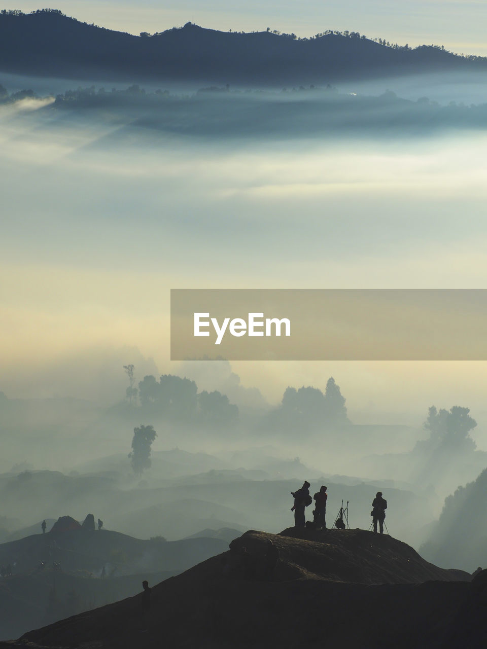 Silhouette people standing on mountain during foggy weather