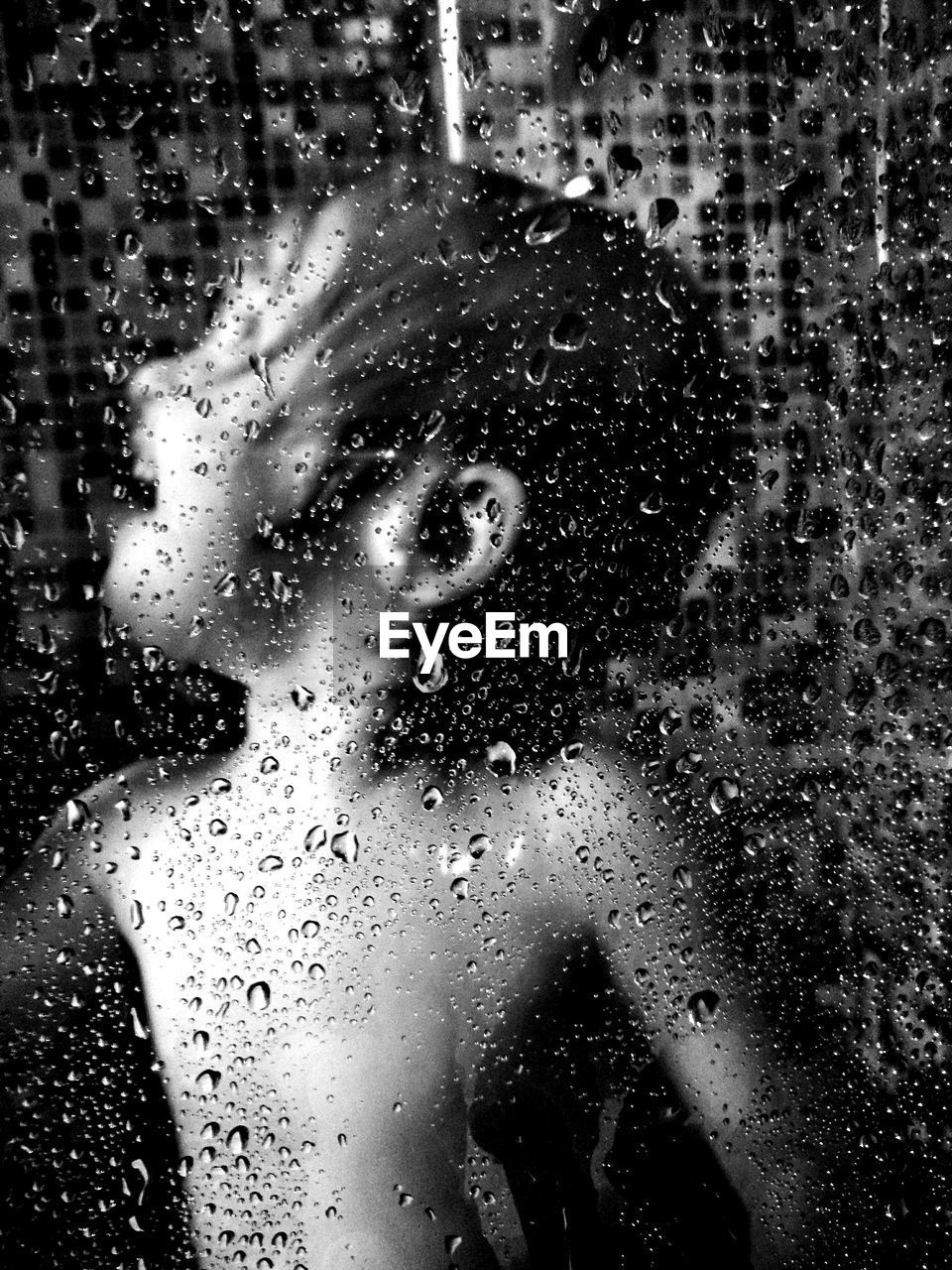 Water drops on glass against boy bathing in bathroom