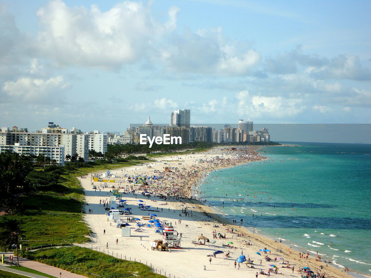 High angle view of cityscape by sea against cloudy sky