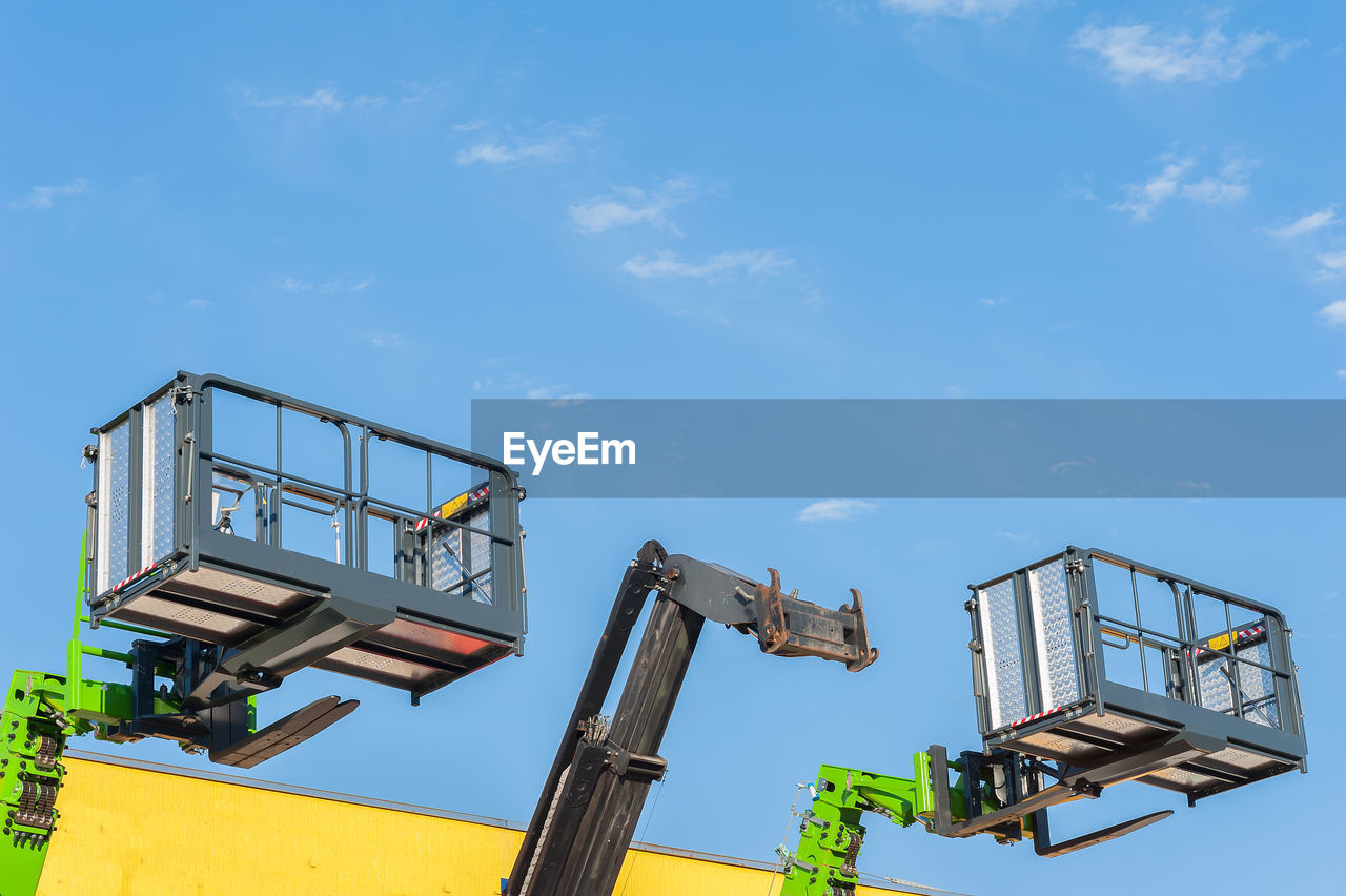 Low angle view lifting platforms against sky