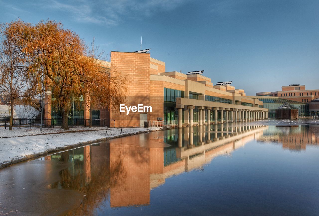 Reflection of buildings and trees in lake against sky