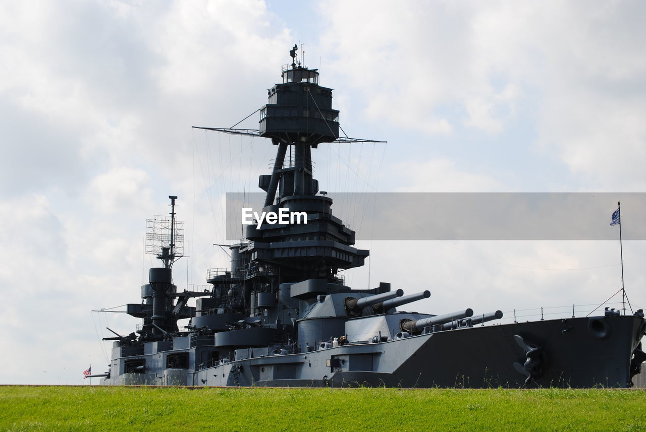 Battleship on field against sky