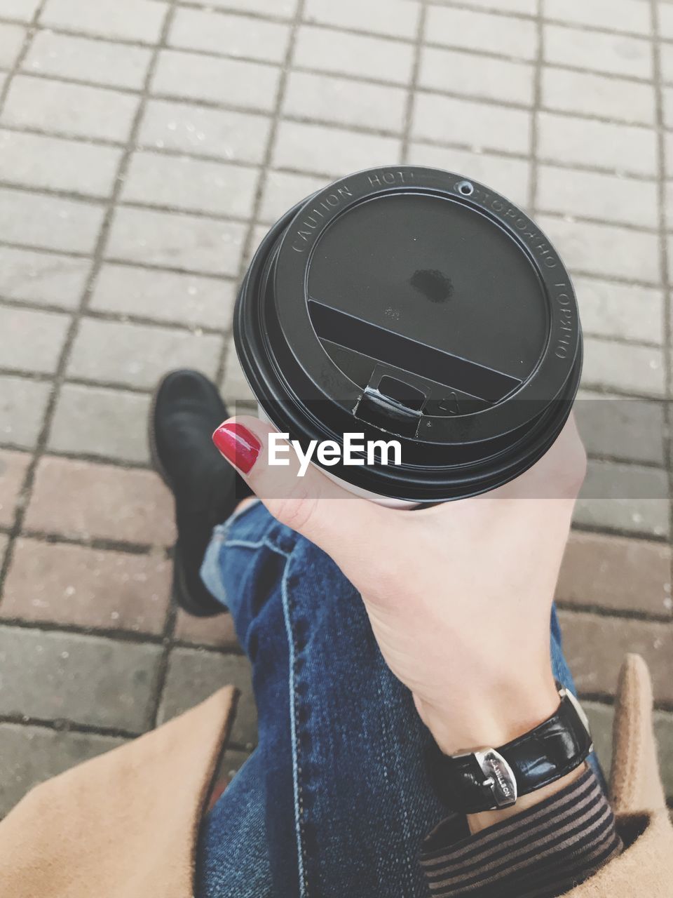 Low section of woman holding disposable cup