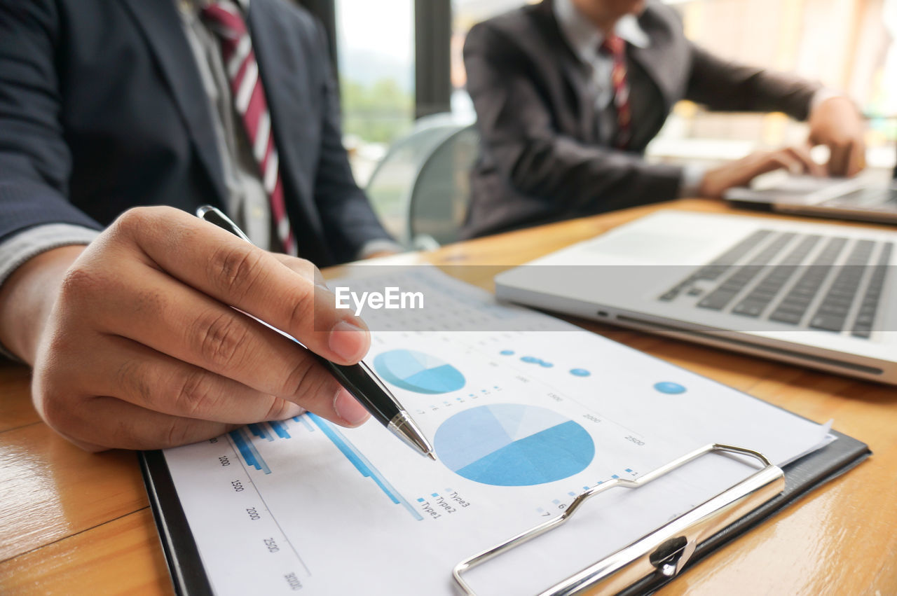 midsection of business colleagues working at table