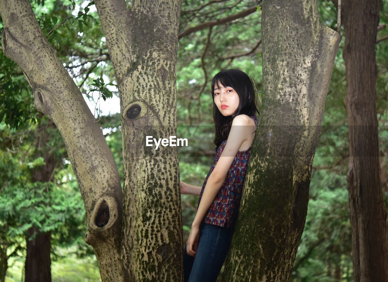 Side view of woman standing by tree