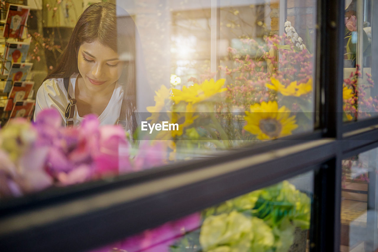 Woman looking at flowers seen through shop window