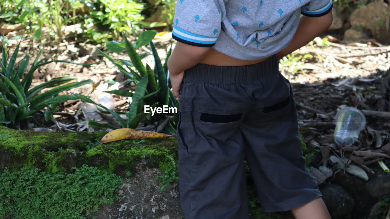 MIDSECTION OF MAN HOLDING PLANTS ON FIELD