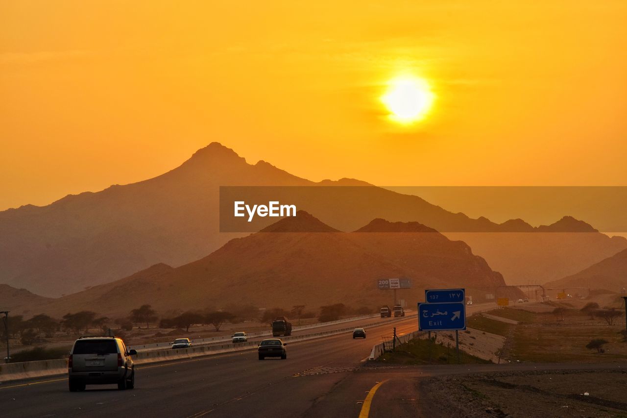 ROAD BY MOUNTAIN AGAINST ORANGE SKY