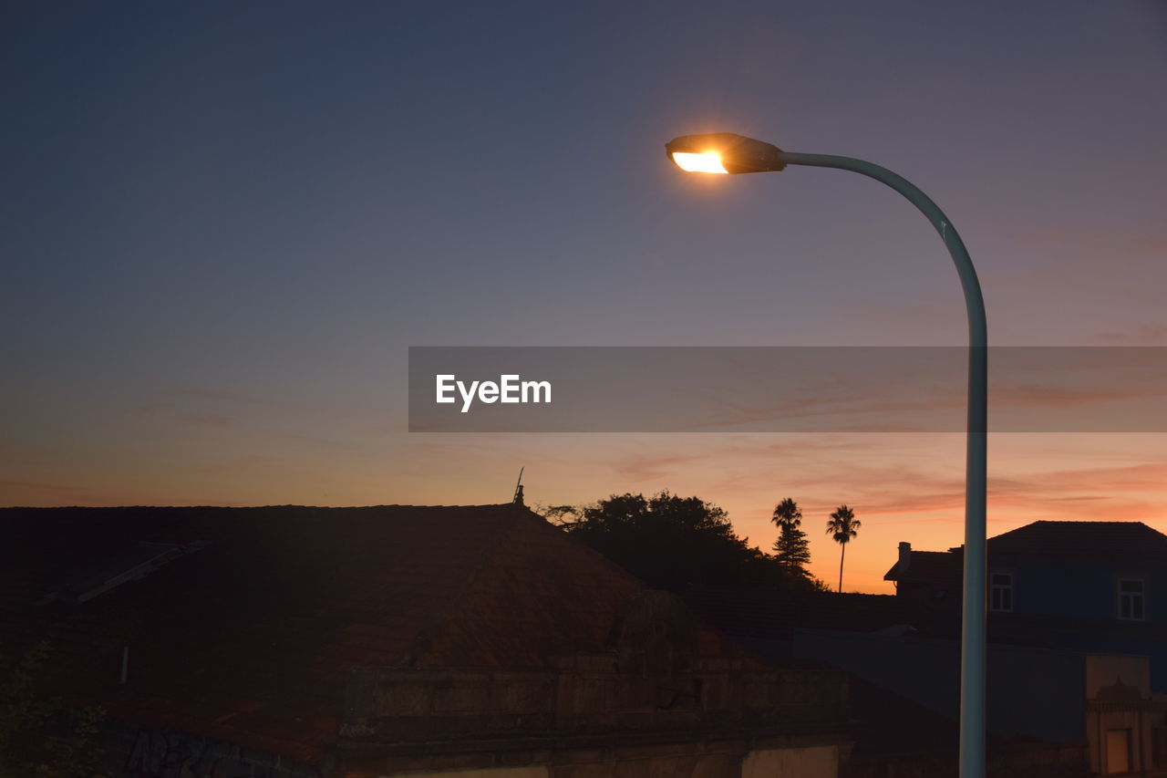 STREET LIGHT AND SILHOUETTE BUILDING AGAINST SKY AT SUNSET