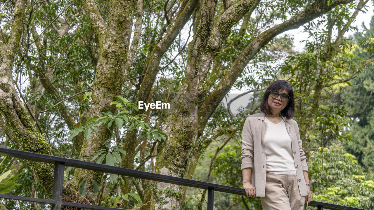 Smiling young woman standing against trees