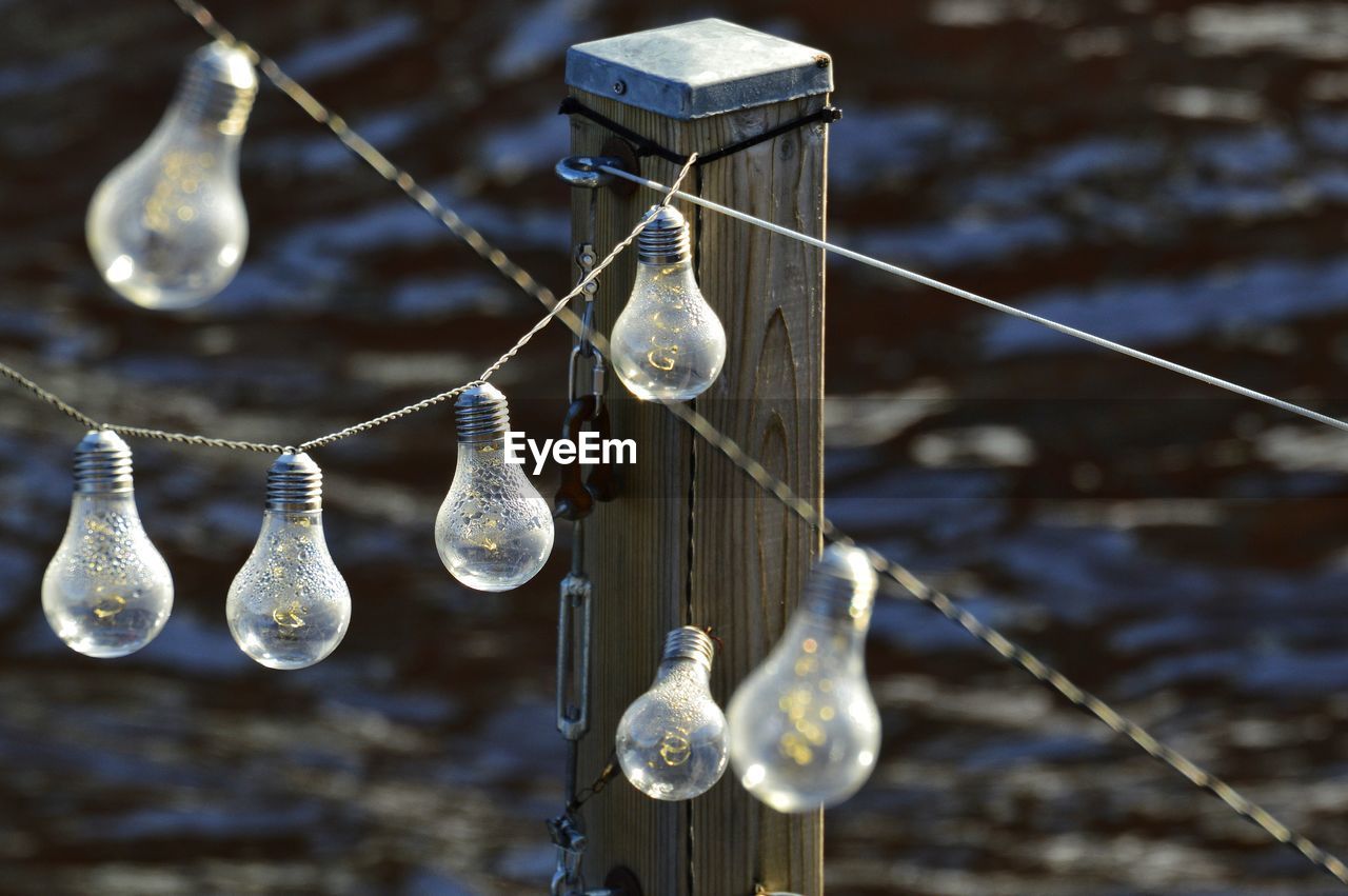 Low angle view of light bulb hanging over water