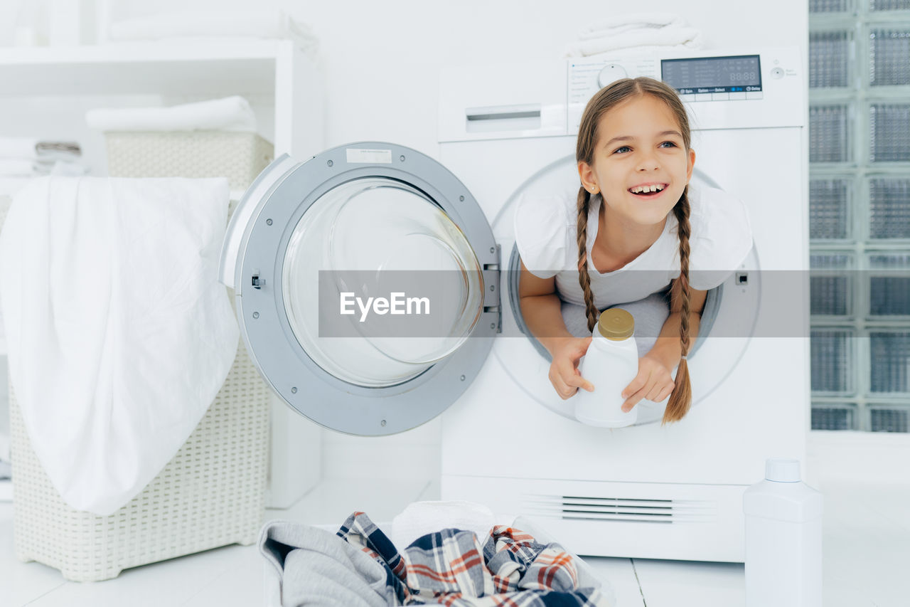 Smiling girl in washing machine at home