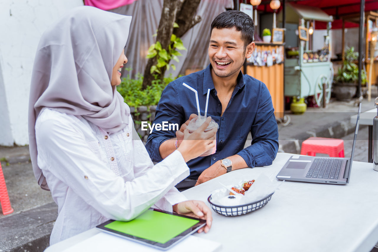 portrait of female friends using mobile phone while sitting at table
