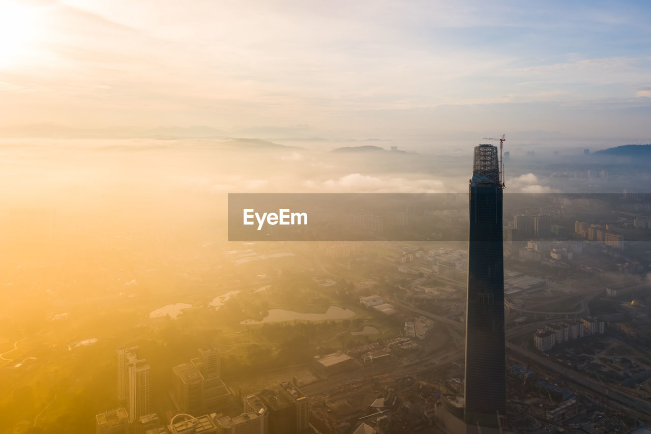 HIGH ANGLE VIEW OF SMOKE AND BUILDINGS AGAINST SKY