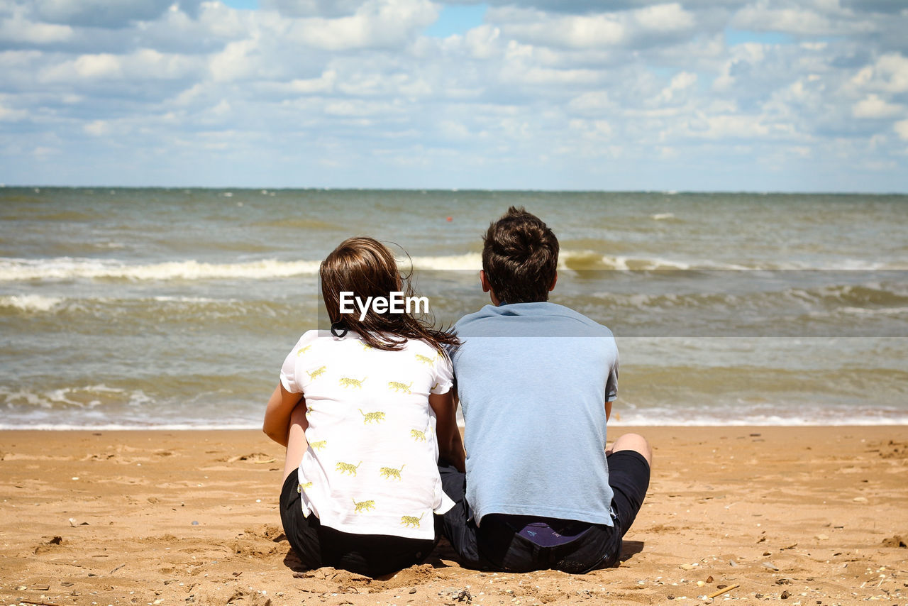 Rear view of couple sitting on beach