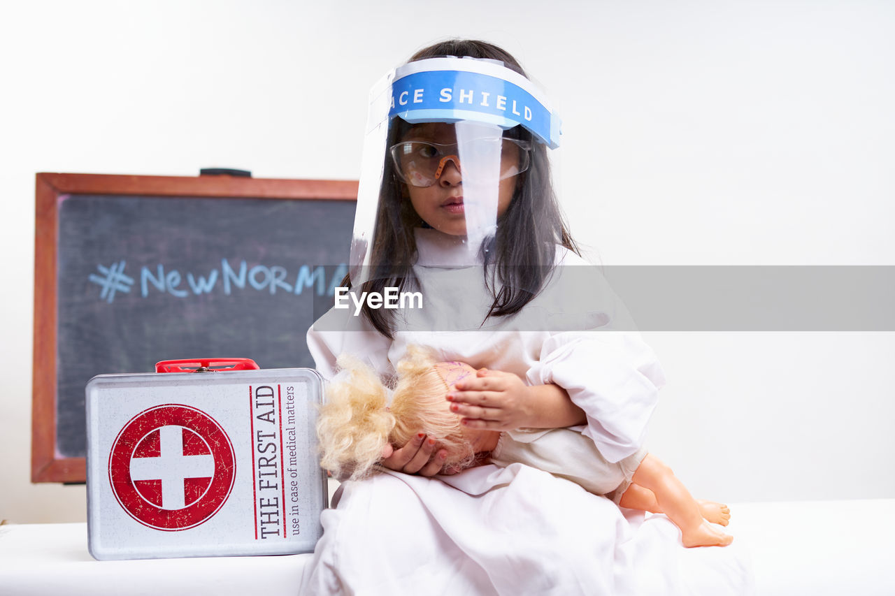 Little girl playing a baby doll at home quarantine