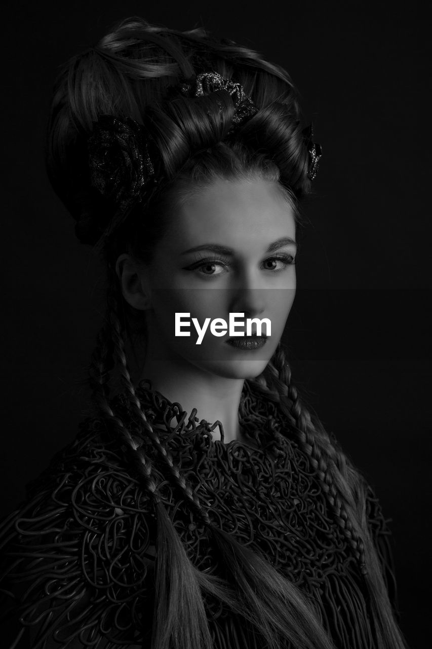 Portrait of young woman against black background