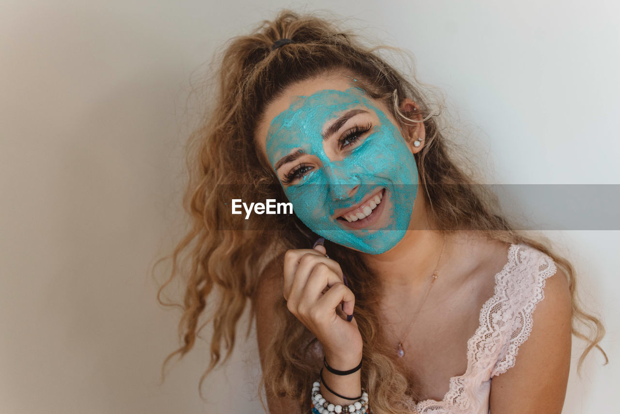 Close-up portrait of smiling woman wearing blue face mask at home