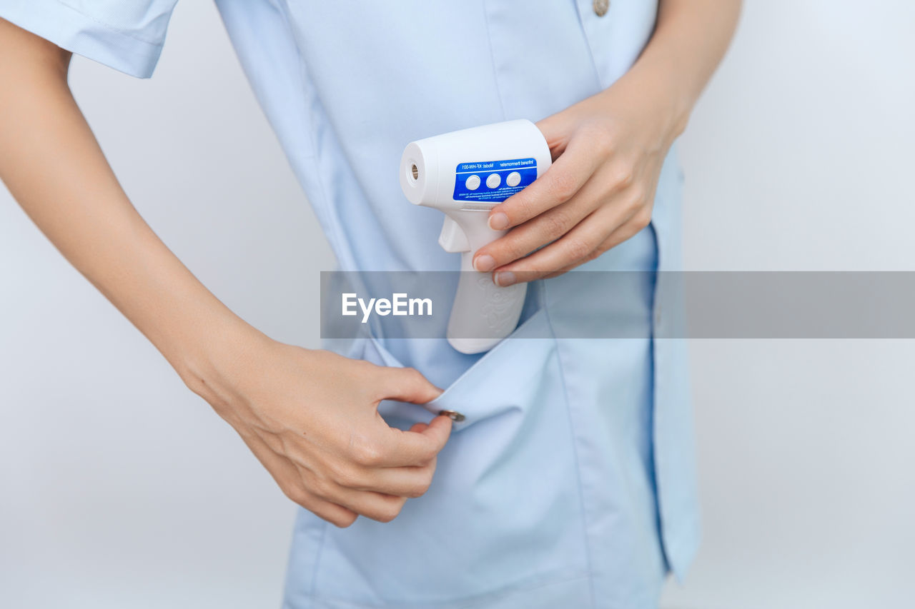 Temperature measurement gun in doctor hands. close-up of doctor wearing protective surgical mask