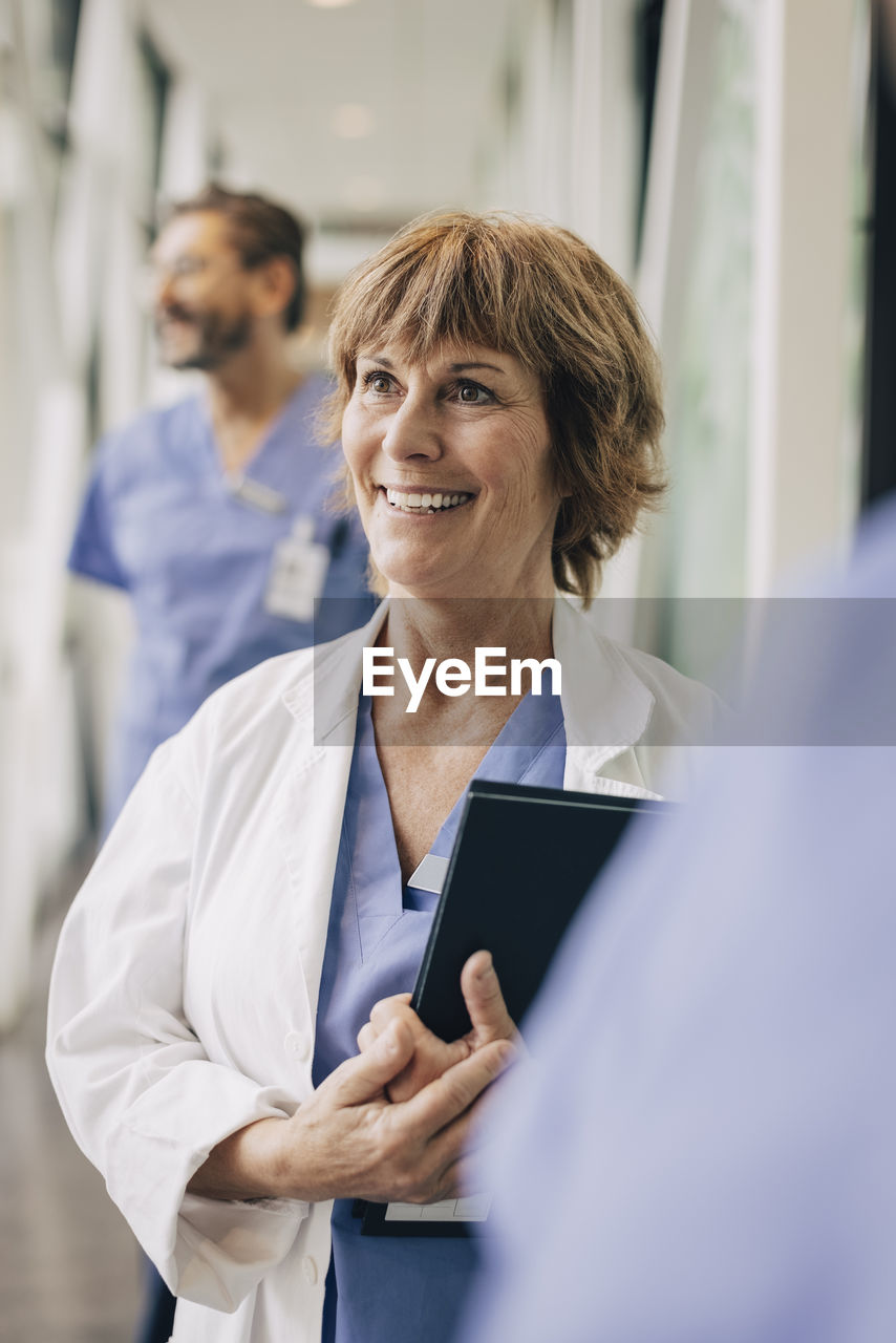 Happy female doctor looking away while standing in hospital