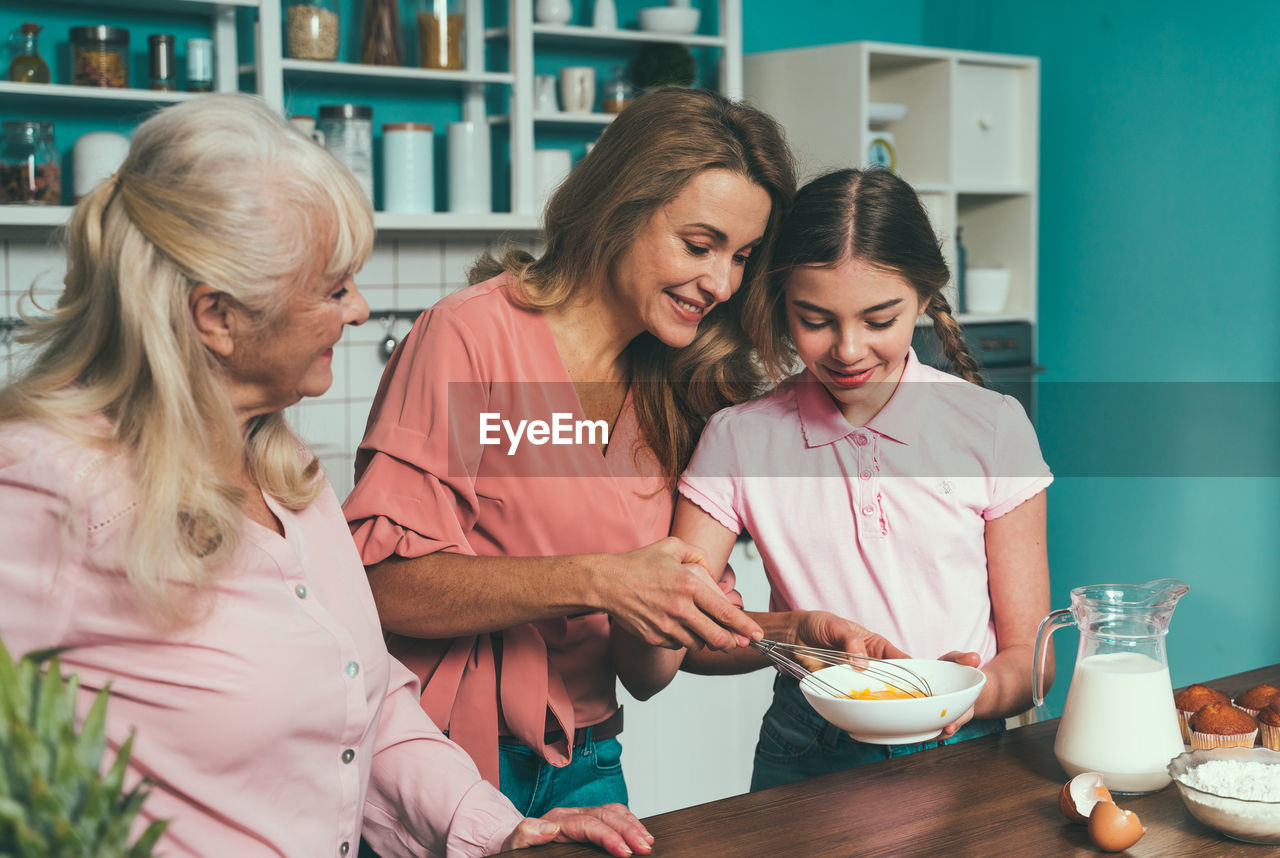 Cheerful daughter with parents preparing food at kitchen