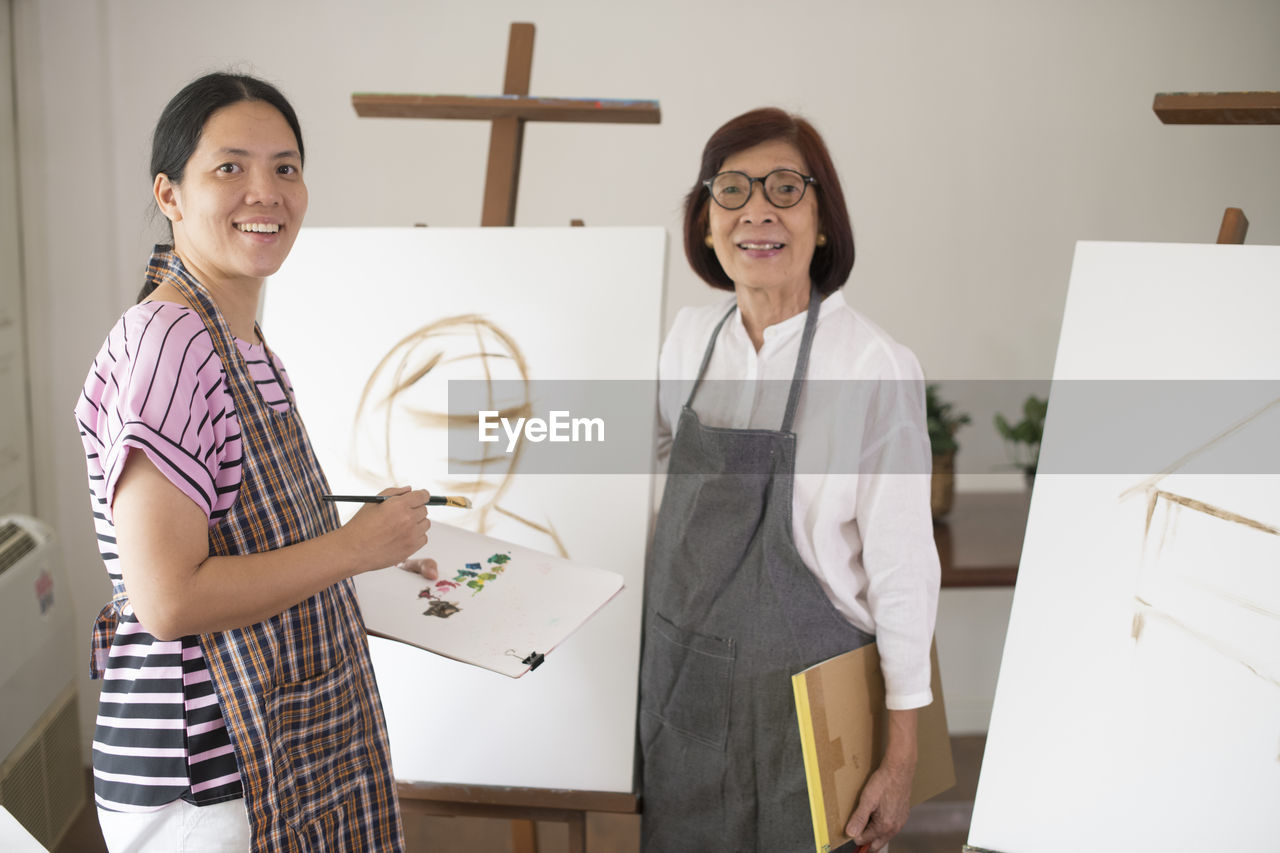 Portrait of women painting on canvas at home