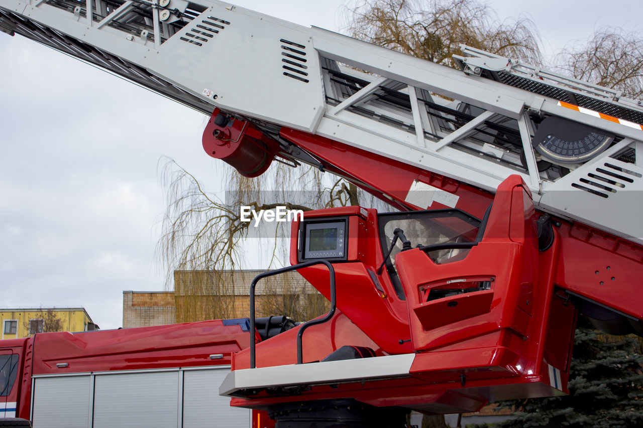 Red fire truck with raised ladder, rescue cabin, control panel, and equipment.