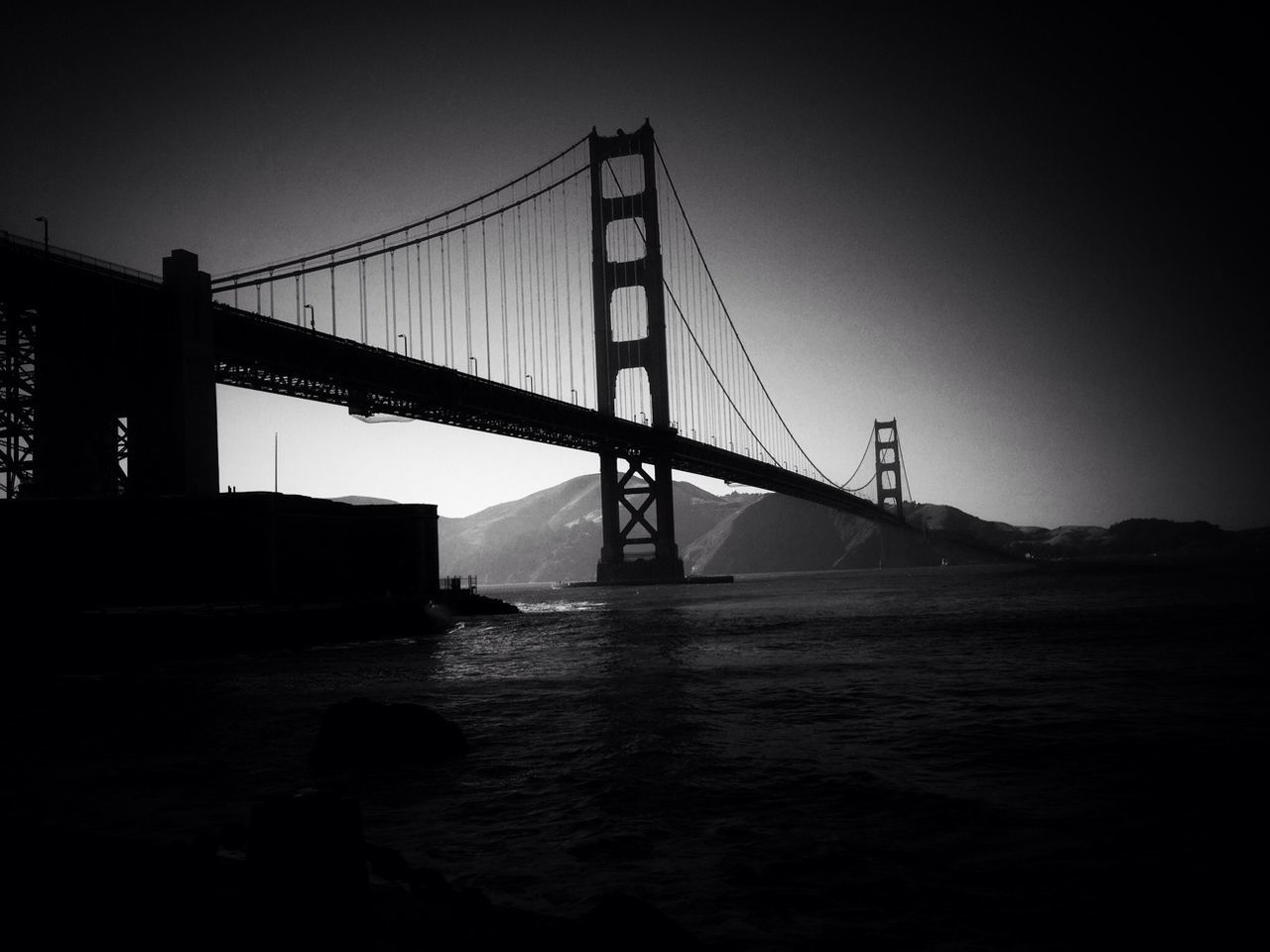 SUSPENSION BRIDGE OVER RIVER AT SUNSET