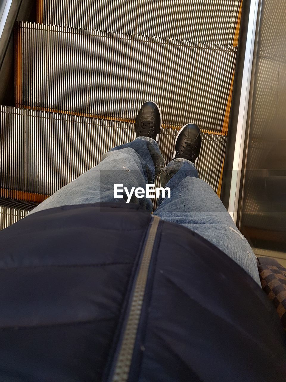 Low section of man standing on escalator