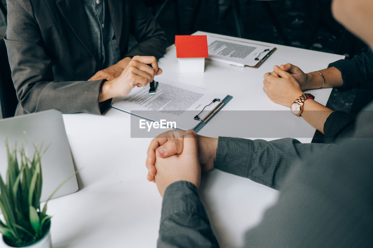 Midsection of real estate agent using rubber stamp on table 