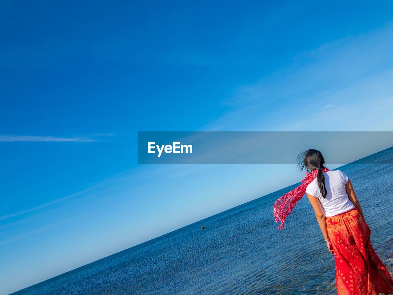 WOMAN STANDING IN SEA AGAINST SKY